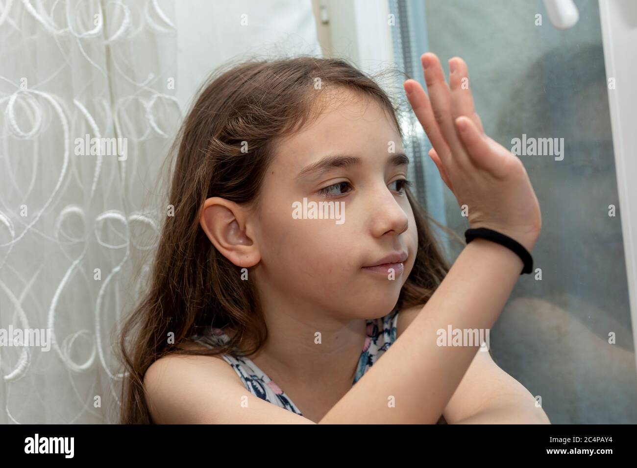 Sorridente bambina in attesa dietro la finestra Foto Stock