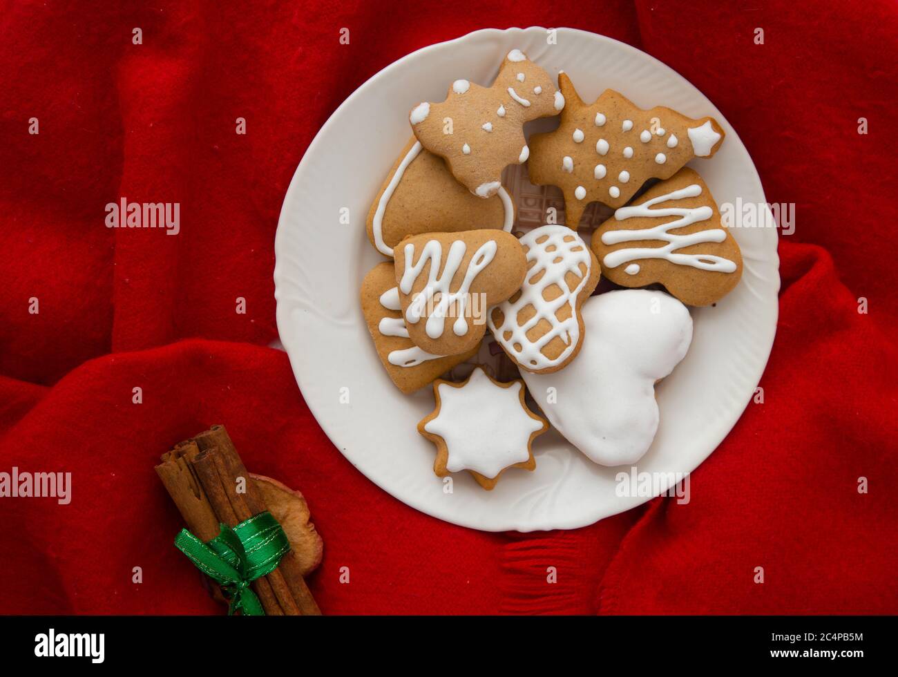 Biscotti natalizi smaltati di forma diversa. Fuoco albero pan di zenzero, cuore forma pan di zenzero e orsacchiotto pan di zenzero con sfondo rosso. Foto Stock