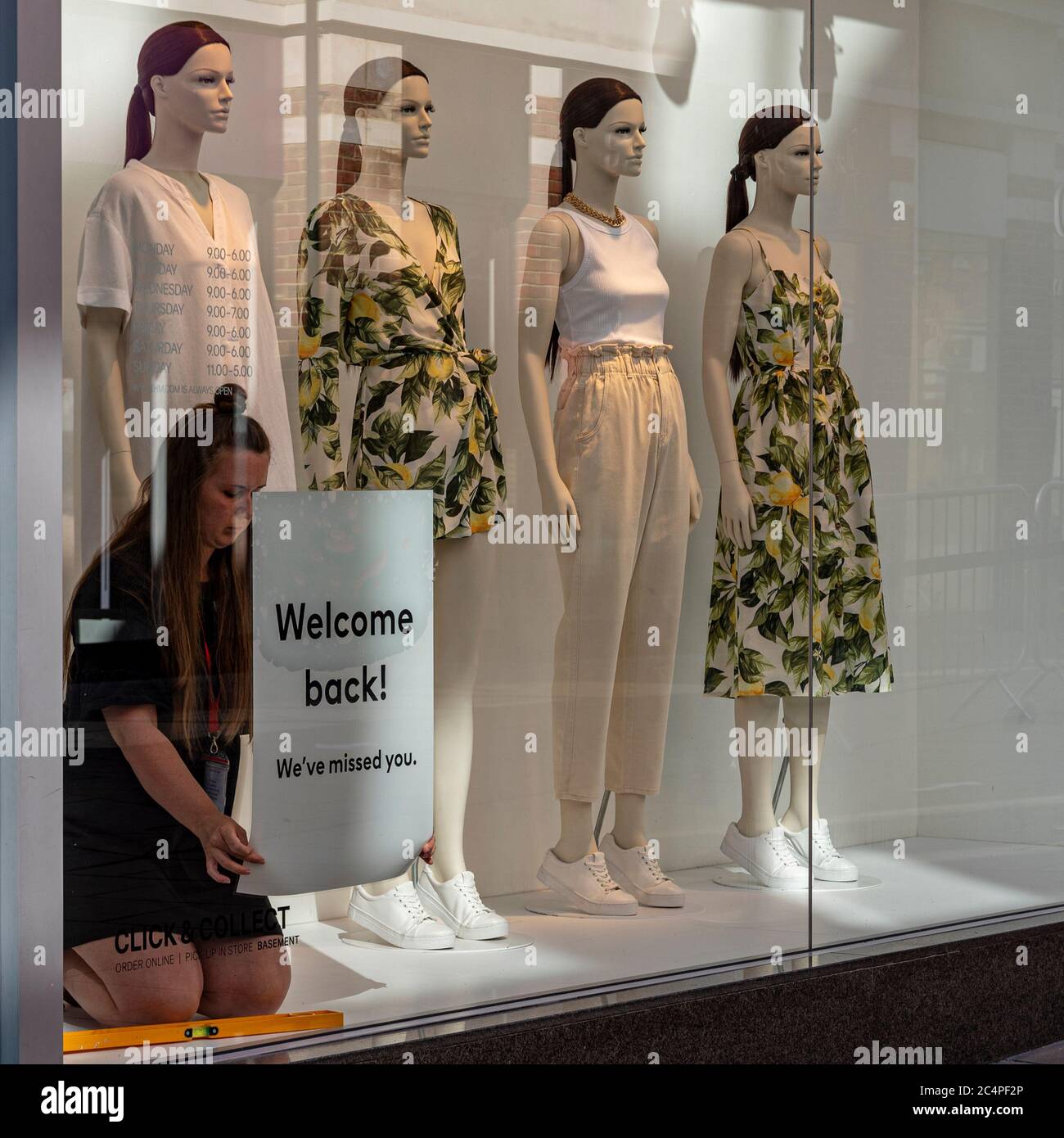 Un lavoratore mette un cartello di benvenuto nella vetrina, il primo giorno che negozi non essenziali hanno aperto a Canterbury Regno Unito dopo il covid-19 blocco. 15 giugno Foto Stock