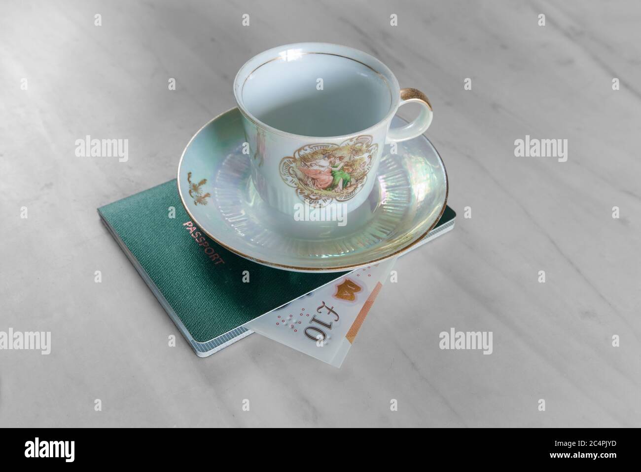 Una banconota da 10 sterline nel passaporto e una classica tazza da tè in più. Foto Stock