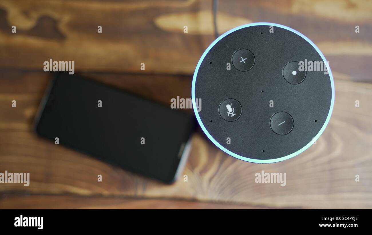 Grigio scuro Amazon Alexa Echo nero e smartphone sul tavolo di legno in un soggiorno Foto Stock
