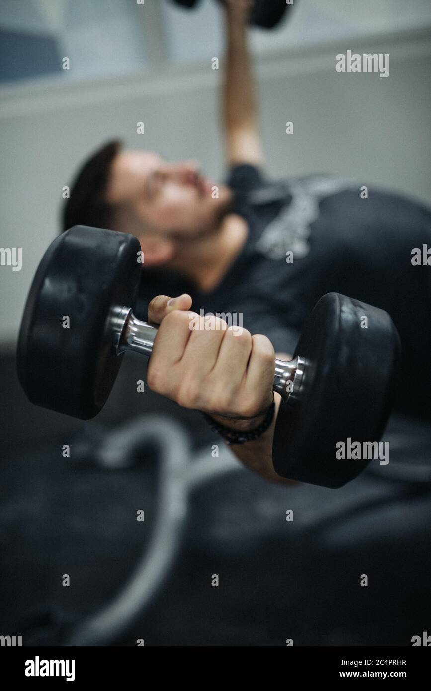 Primo piano immagine giovane uomo sollevamento pesi in palestra. Foto Stock