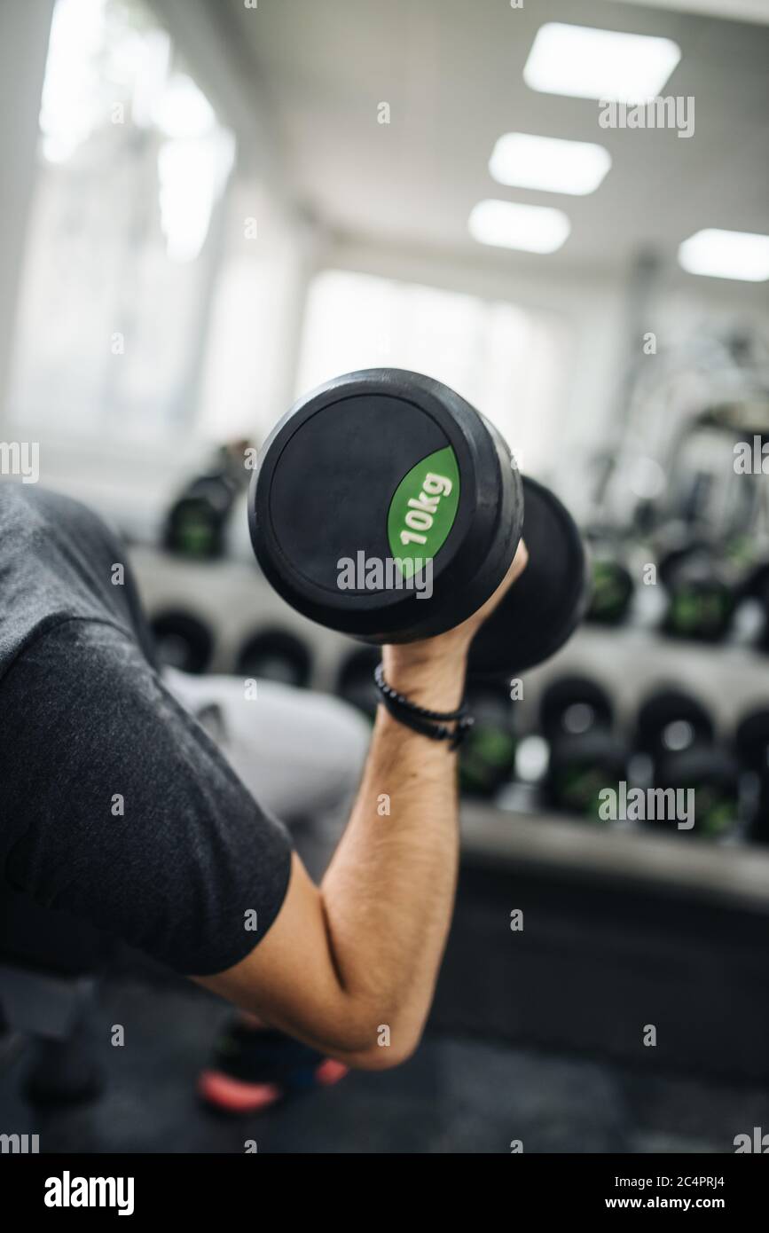 Primo piano immagine giovane uomo muscolare sollevamento pesi in palestra Foto Stock