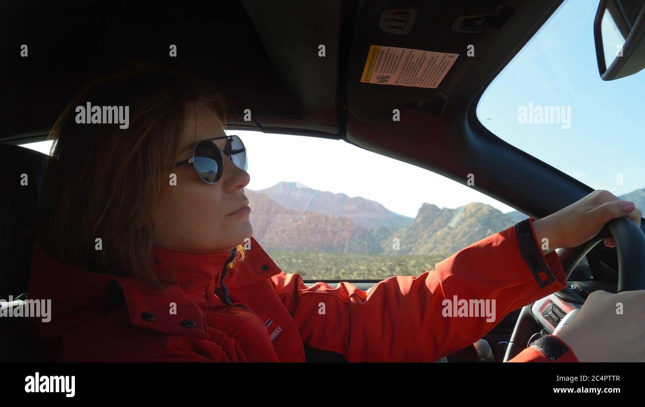 La giovane donna guida un'auto in una giornata di sole Foto Stock