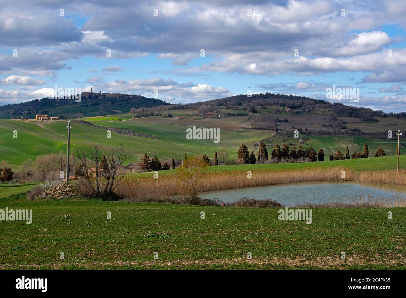 Piccole strade con cipressi mediterranei, casali e verdi colline, un paesaggio tipico della Toscana, Italia Foto Stock