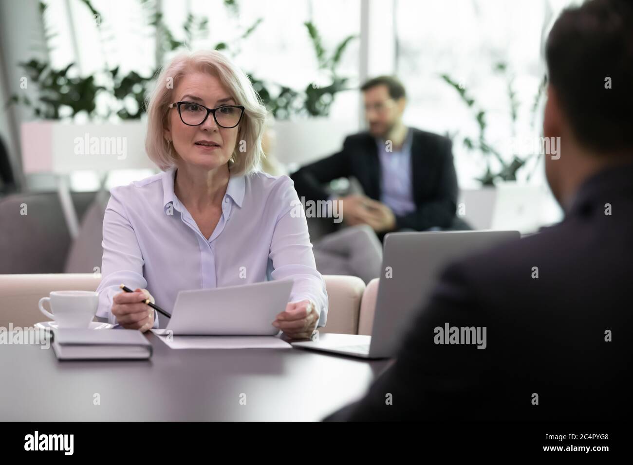 Donna di affari adulta intervista candidato di lavoro che tiene il curriculum Foto Stock