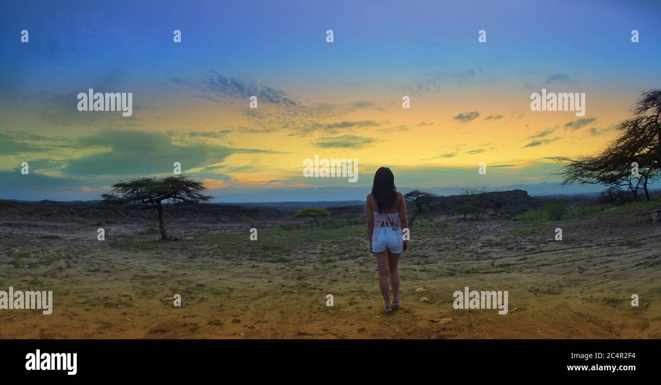 Donna solitaria indietro guardando il tramonto nel deserto de la Tatacoa (deserto di Tatacoa) a Villavieja, Huila / Colombia Foto Stock