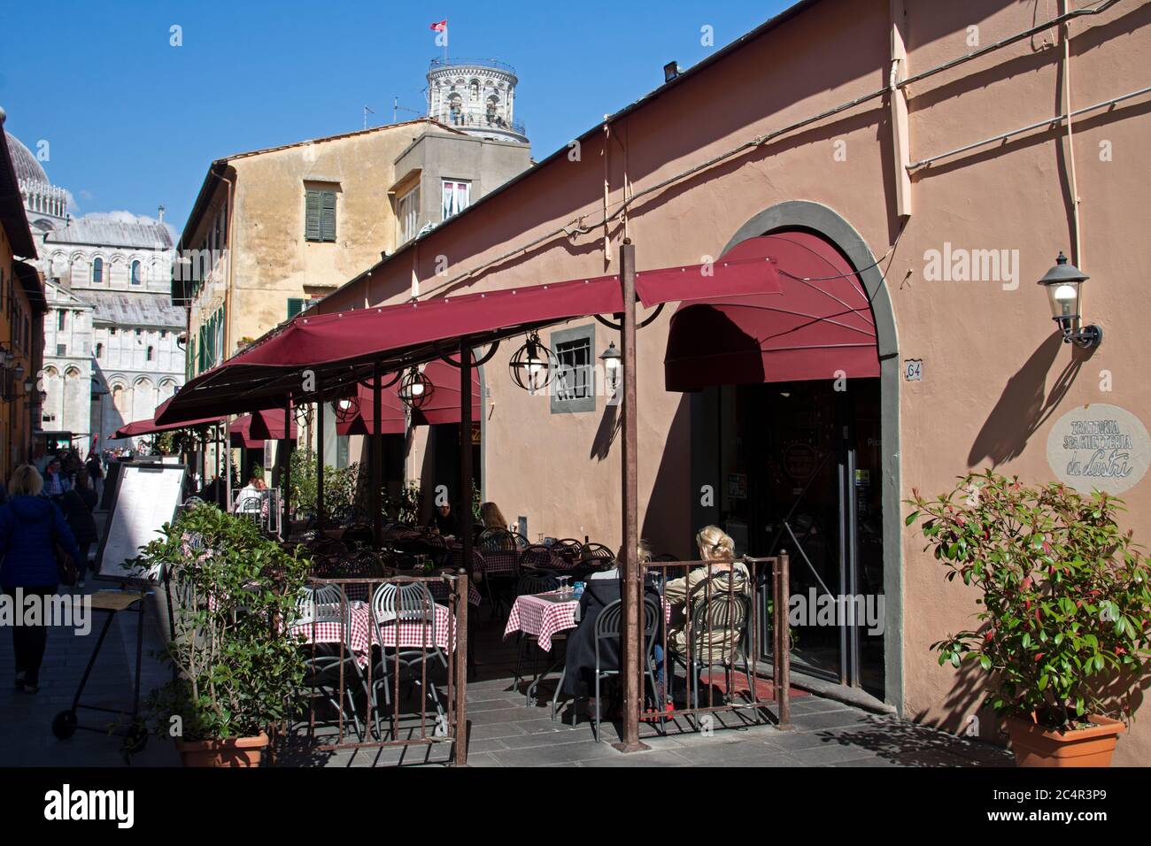 Posti a sedere all'aperto in un ristorante in Via Santa Maria con la Torre Pendente di Pisa alle spalle, Pisa, Toscana, Italia Foto Stock