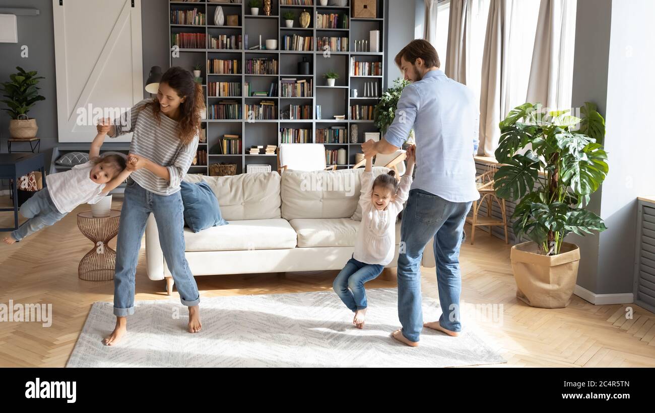 Felici giovani genitori filando ridendo piccole figlie, divertendosi Foto Stock