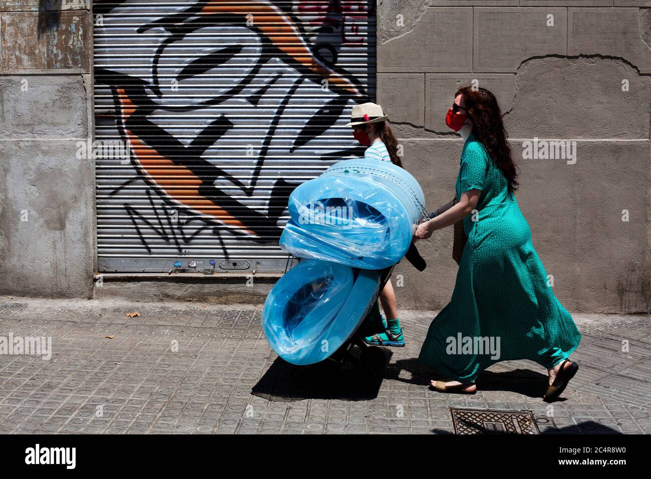 Una donna spagnola spinge due materassi a casa su un carrello. Foto Stock