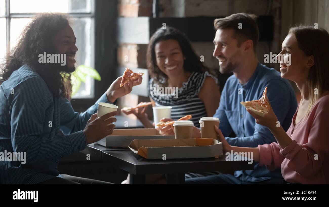 Gli amici seduti al bar mangiano pizza, bevono caffè, godono di comunicazione Foto Stock