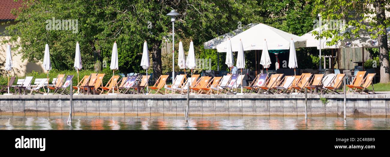 Sedie a sdraio e ombrelloni sono allineati al ristorante sul lungolago del lago Starnberg. È il momento di rilassarsi e rilassarsi! Foto Stock