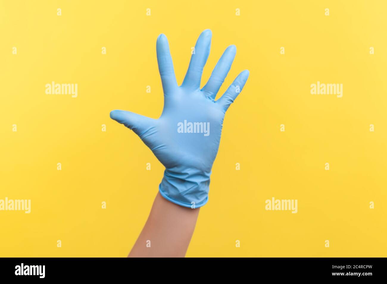 Profilo Vista laterale primo piano della mano umana in guanti chirurgici blu che mostrano il numero cinque con la mano o con la mano che ondeggiano per salutare. Interno, studio shot, isolare Foto Stock