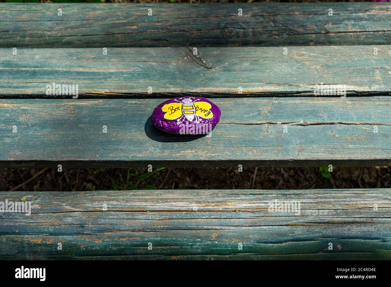 Pebble viola dipinto con IL LOGO Bees su un banco in bassa Baviera Germania Foto Stock