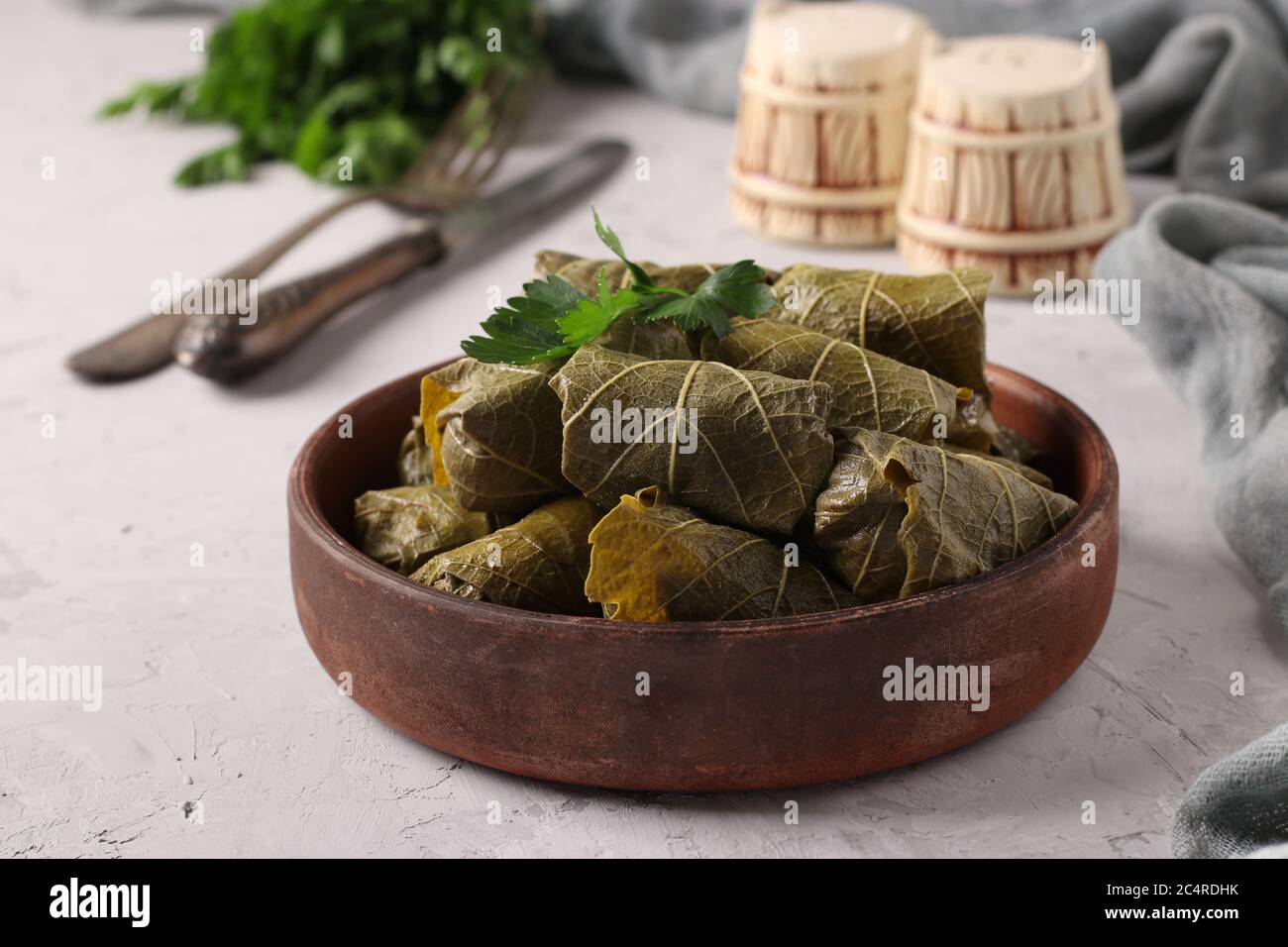 Dolma - foglie di uva farcite con riso e carne su fondo grigio chiaro. Cucina tradizionale caucasica, greca, ottomana e turca, Closeup Foto Stock