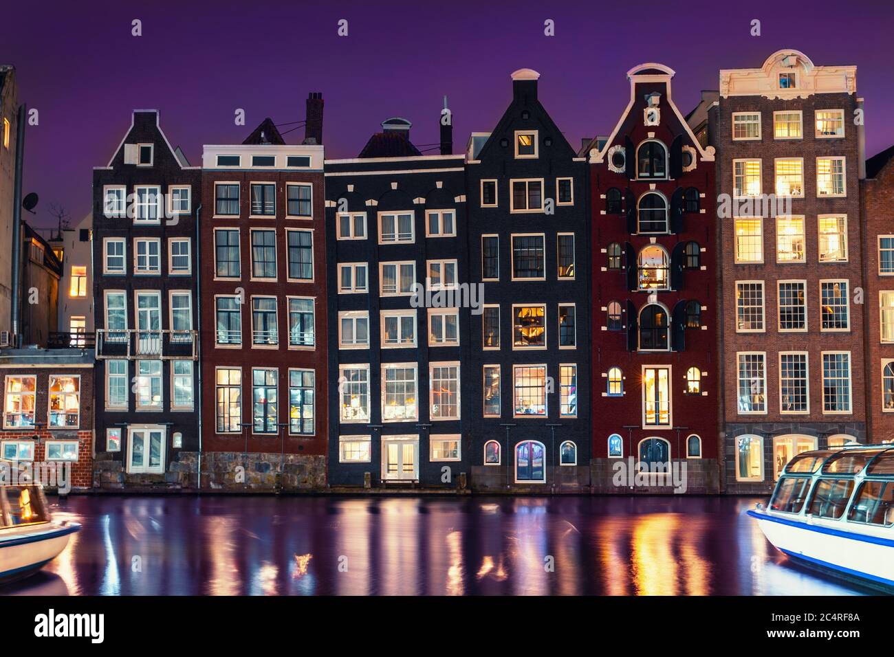 Amsterdam di notte, le case da ballo olandesi si riflettono nel fiume Amstel, la vecchia città europea. Foto Stock