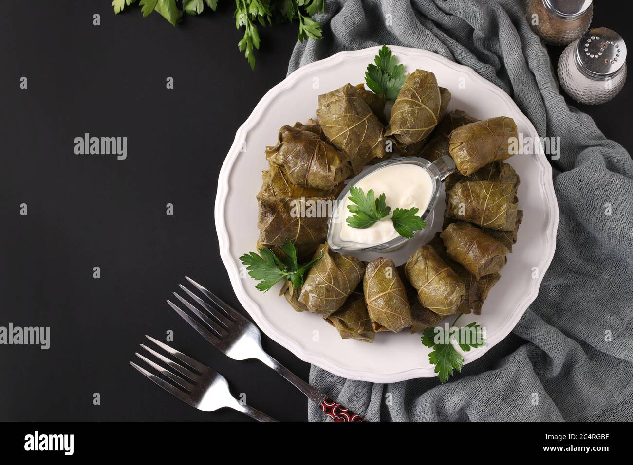 Dolma - foglie di uva ripieni con riso e carne su piatto bianco su fondo nero. Cucina tradizionale caucasica, greca, ottomana e turca Foto Stock