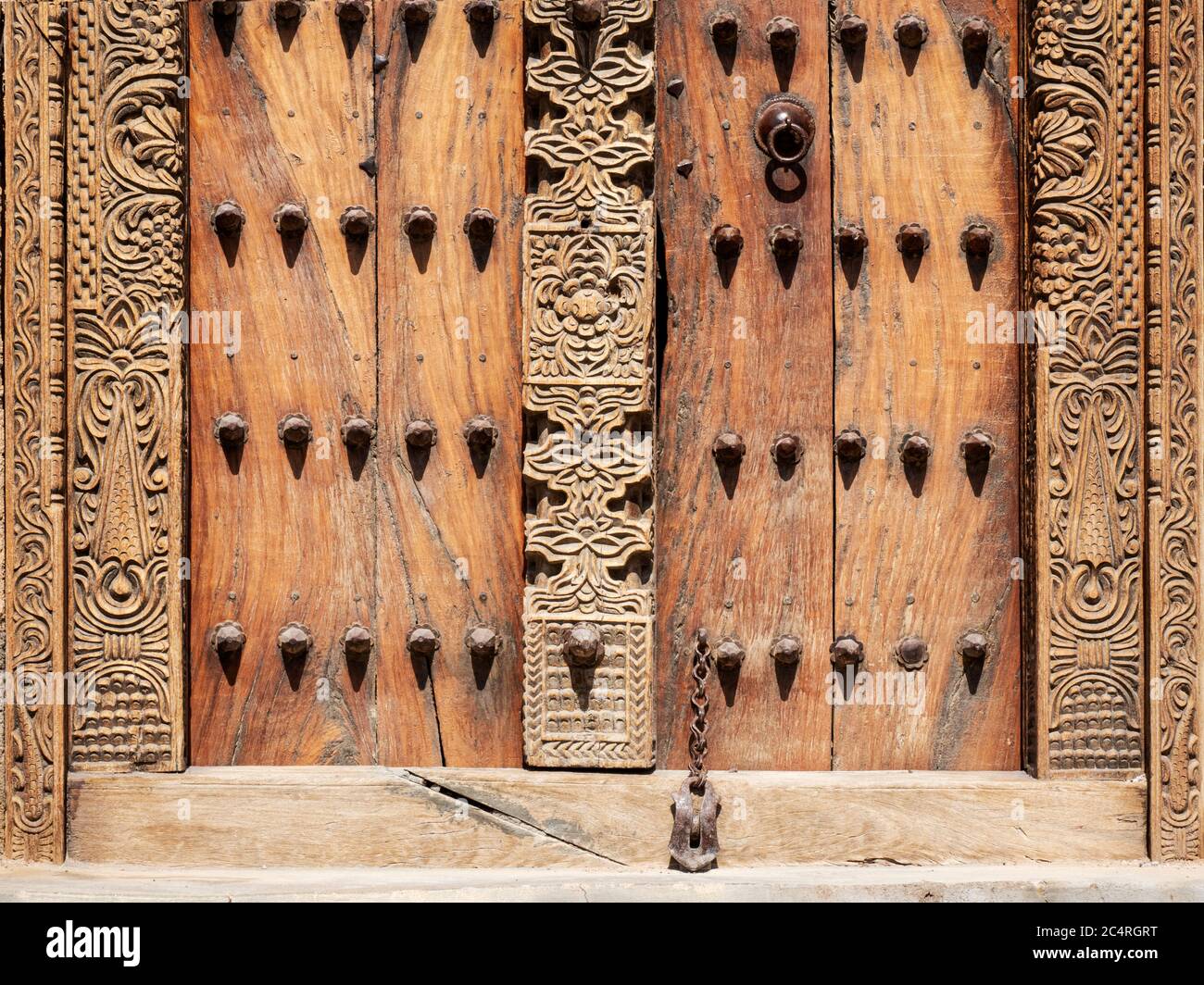 Porta pesante in legno con borchie metalliche, dalle torri di guardia nel villaggio di Mudayrib, Sultanato di Oman. Foto Stock