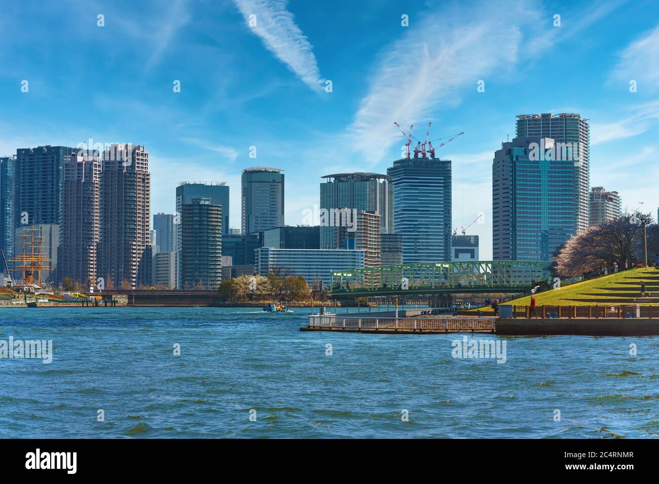 tokyo, giappone - aprile 04 2020: Parco Ishikawajima fiancheggiato da fiori di ciliegio sul fiume Sumida di fronte al ponte AIOI e Meiji Maru barca a vela con sci Foto Stock