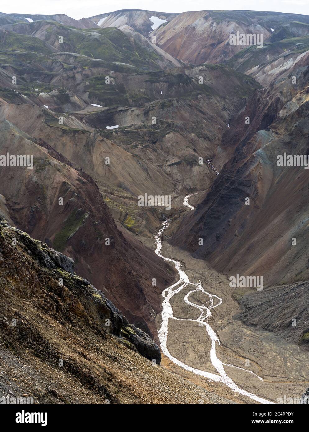 Creek si sta precipitando giù da sciogliendo le macchie di neve in Islanda highlands Foto Stock