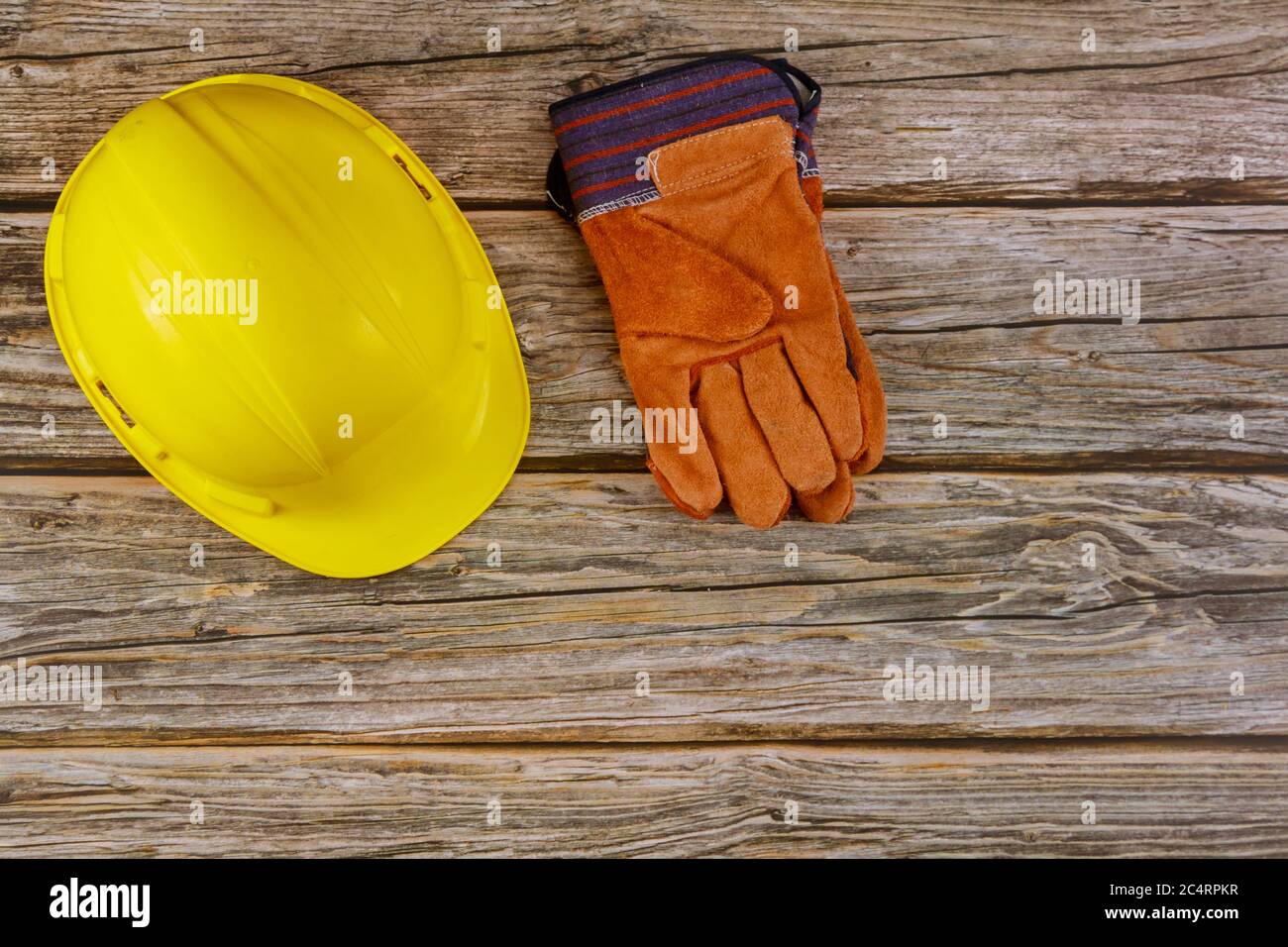 Standard di sicurezza dell'attrezzatura per cantieri, guanti di sicurezza gialli protettivi per elmetti su sfondo di legno Foto Stock