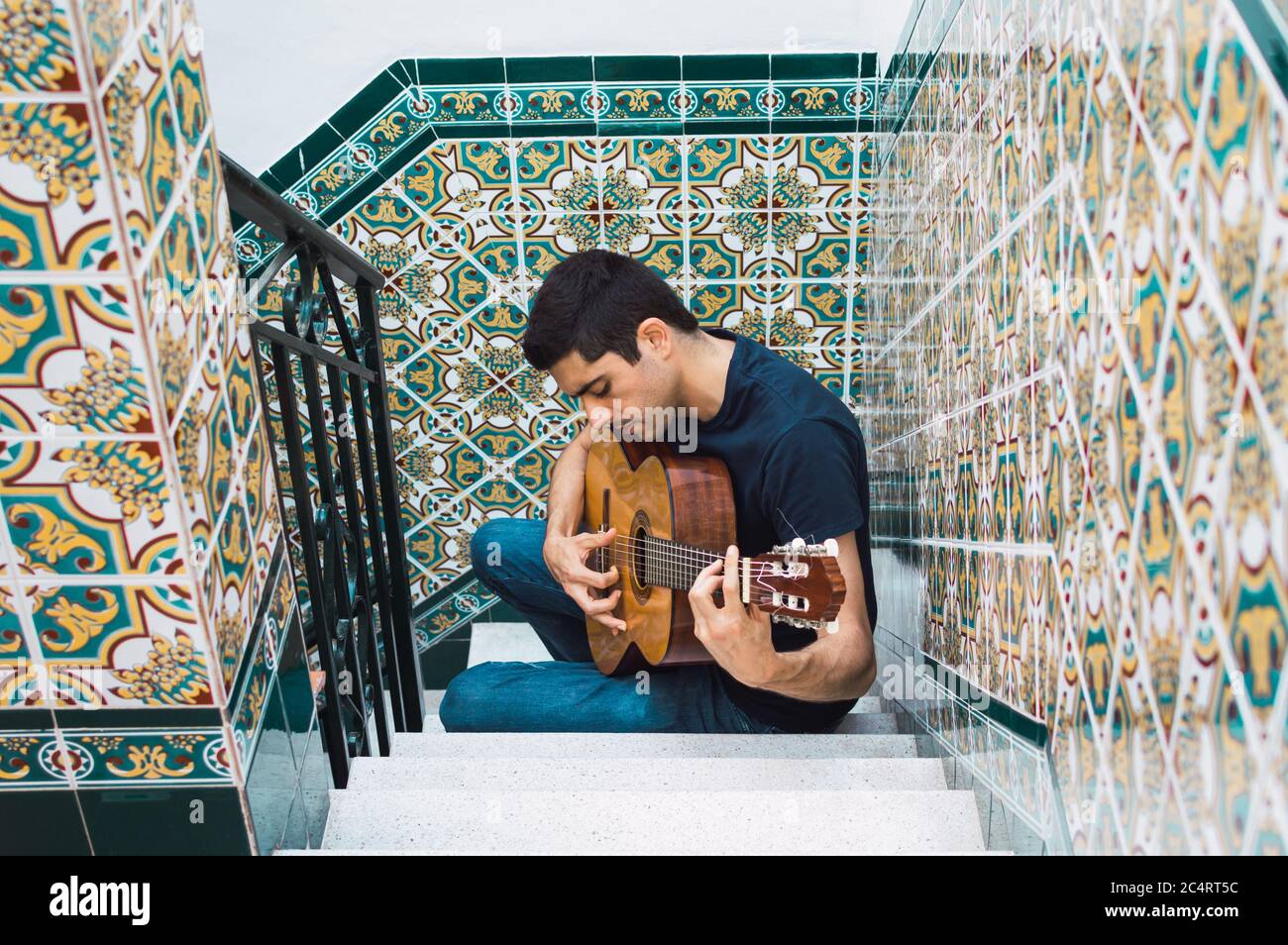 Giovane che suona la chitarra spagnola in un cortile andaluso. Foto Stock