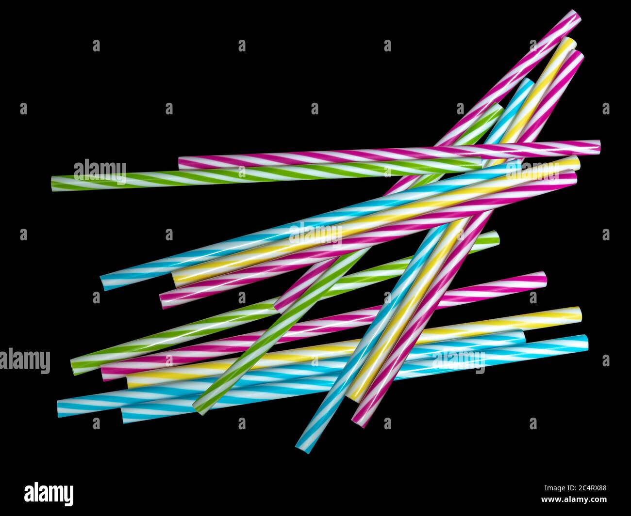 Pile di colorate paglia potabile in plastica a righe, sottoterra nera Foto Stock