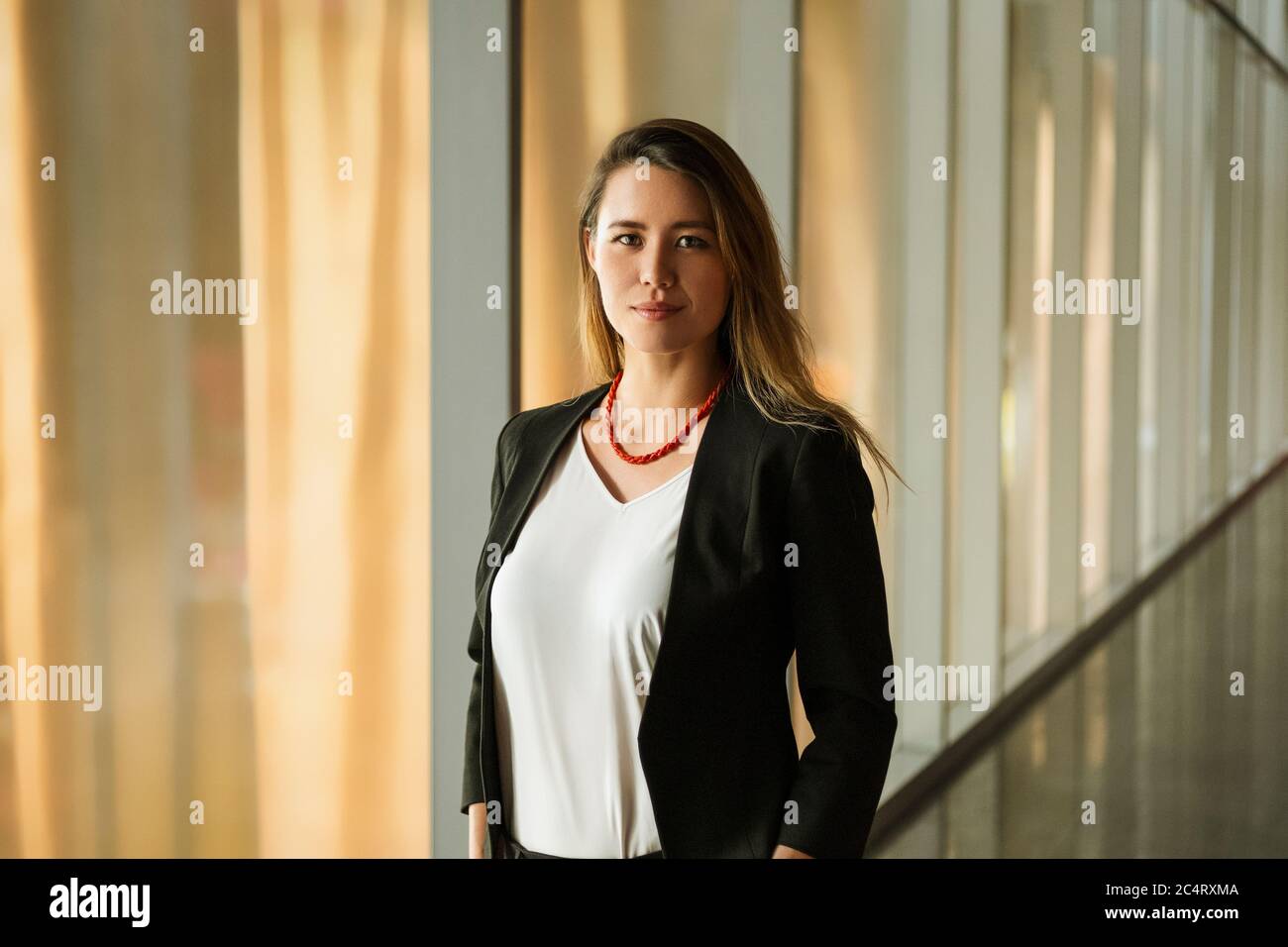 Giovane donna di affari che si trova in piedi nel corridoio corporativo Foto Stock