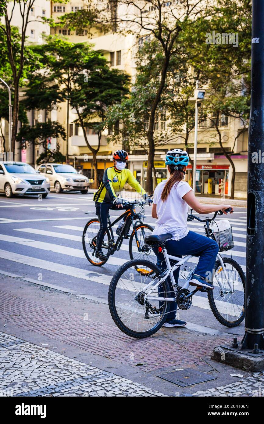 Uomo e donna in bicicletta con maschere facciali nel centro di Belo Horizonte, Brasile, durante la pandemia del Covid-19. Foto Stock