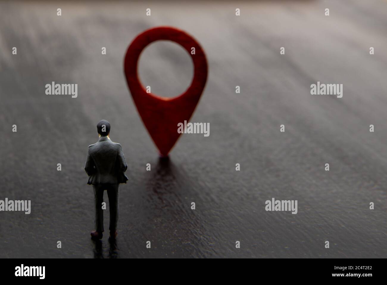 Figurine in miniatura posato come visualizzazione permanente che fa l'uomo d'affari la decisione sulla direzione di raggiungere la destinazione contrassegnata da icona di navigazione rossa, minimi Foto Stock