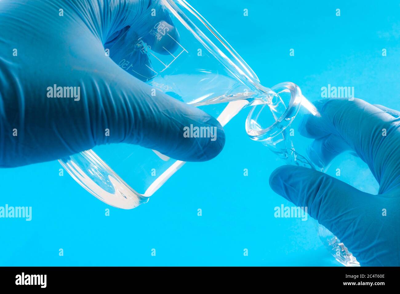 Esperimento scientifico, reazione chimica e concetto di chimica sperimentale con primo piano sulle mani di uno scienziato che indossa guanti di gomma blu e p Foto Stock