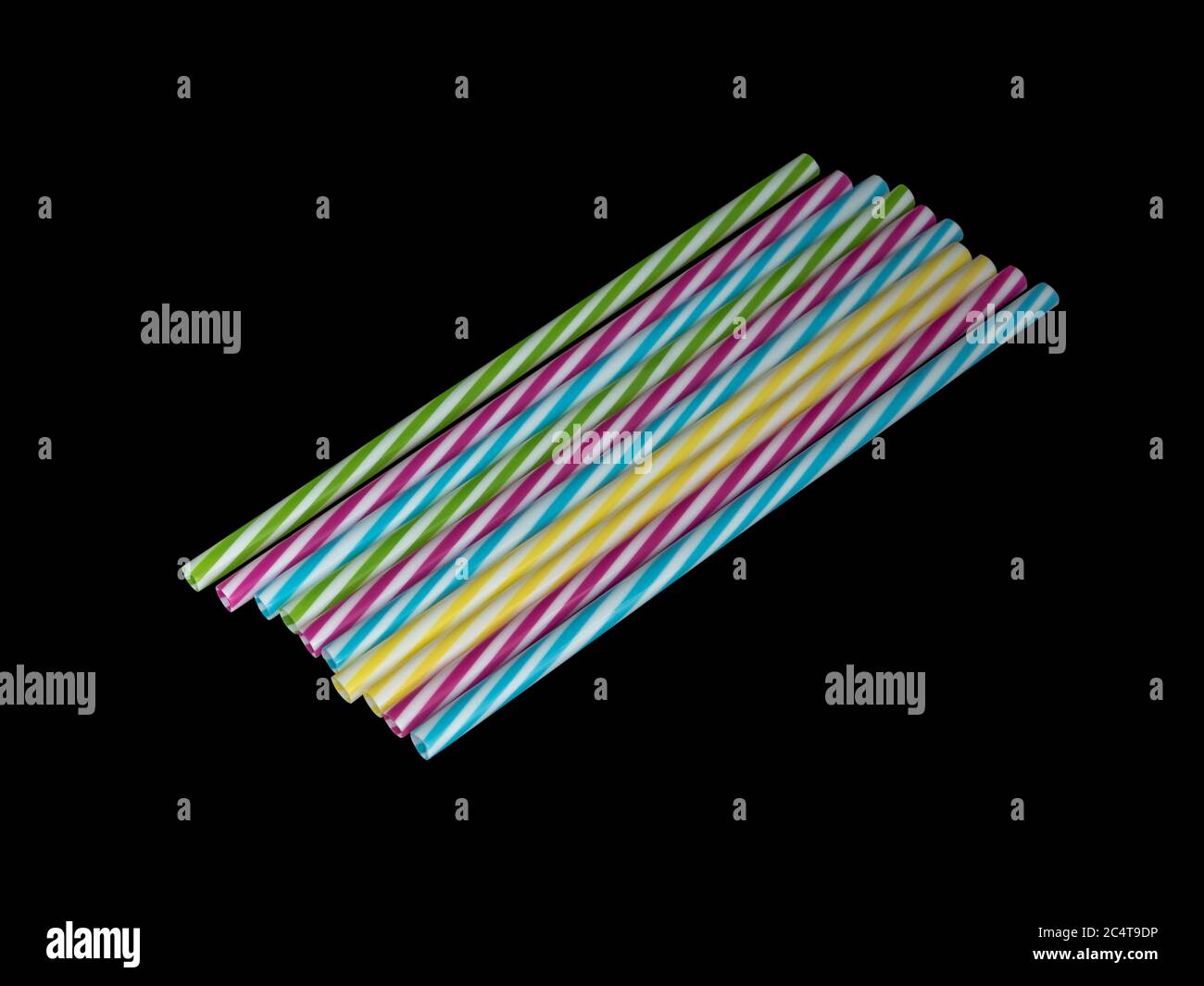 Pile di colorate paglia potabile in plastica a righe, sottoterra nera Foto Stock