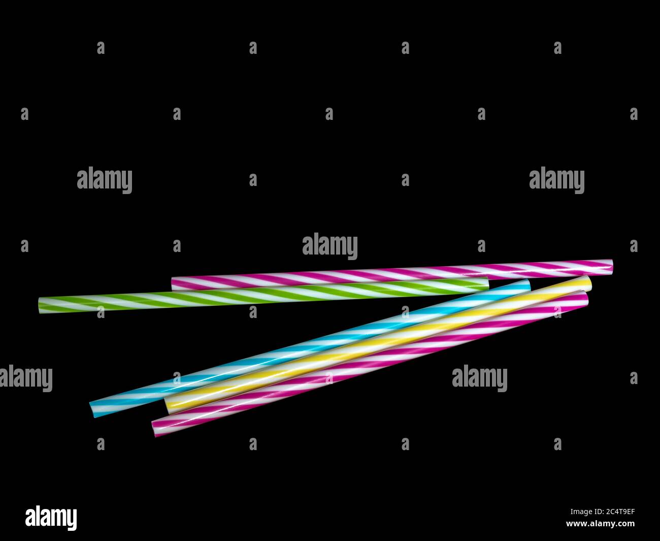 Pile di colorate paglia potabile in plastica a righe, sottoterra nera. Foto Stock