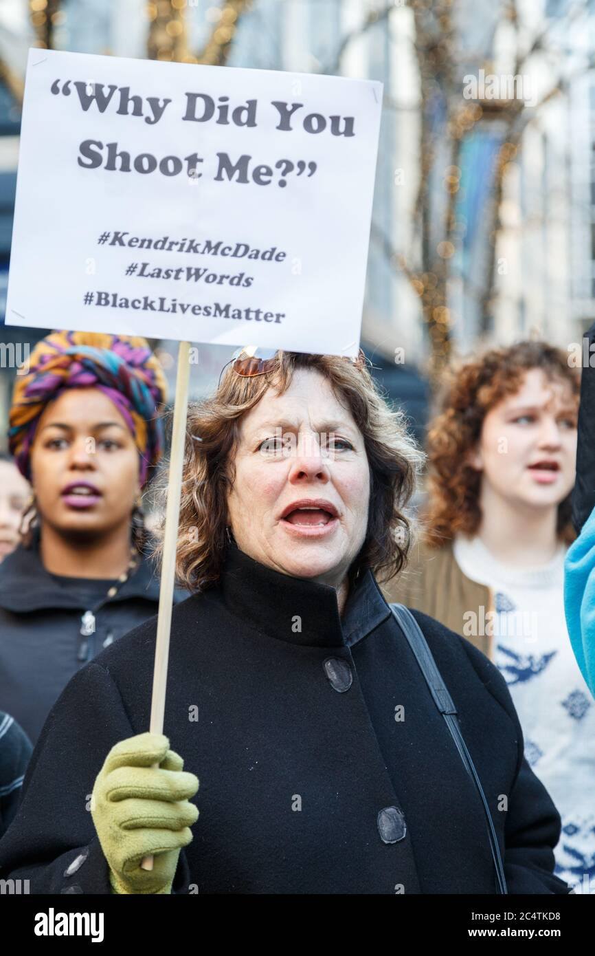 Seattle, Stati Uniti. 27 Novembre 2015. Una donna di protesta caucasica ha un segno che menziona il Kendric McDade, ucciso da due ufficiali di polizia nel 2012. Foto Stock