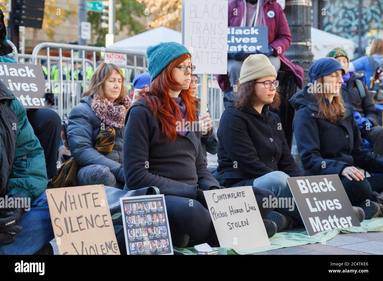 Seattle, Stati Uniti. 27 Novembre 2015. Le donne bianche manifestanti si siedono silenziosamente per il supporto del movimento Black Lives Matter. Foto Stock