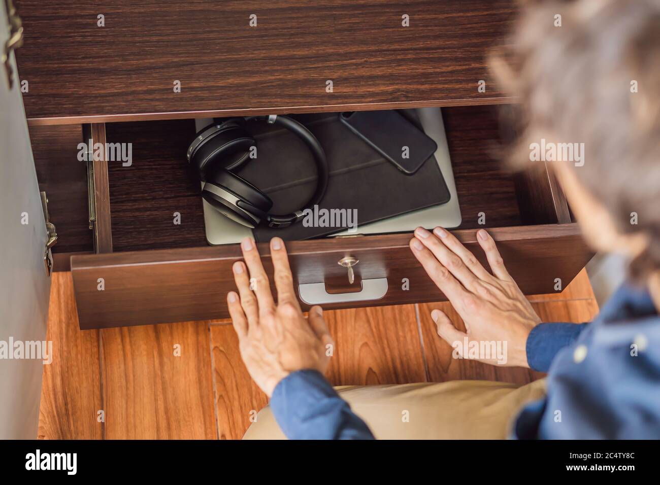 Un uomo mette i gadget in un armadietto per la disintossicazione digitale Foto Stock