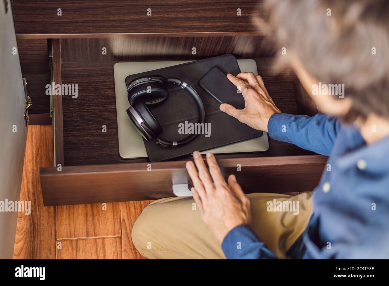 Un uomo mette i gadget in un armadietto per la disintossicazione digitale Foto Stock