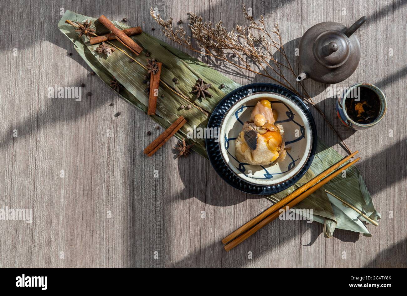 Gnocchi di riso cinese (Zongzi) a forma di piramide avvolto da foglie ingredienti su ciotola stile cinese e bastoncini di pollo serviti con tè cinese. Famoso come Foto Stock