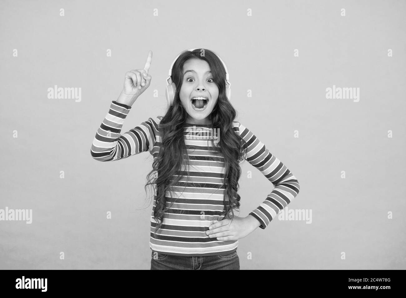ho avuto un'idea. bambina ascolta musica in cuffia. audio libro letteratura per bambini. teen kid esprimere positività. studentessa ottimista indossa abiti colorati. ispirata alla canzone. su tono positivo. Foto Stock