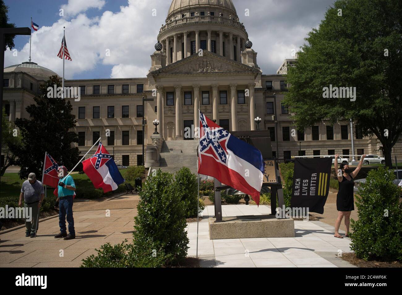 (200629) -- JACKSON, 29 giugno 2020 (Xinhua) -- manifestanti (L) contro il cambio della bandiera dello Stato del Mississippi, e un manifestante (R) con bandiera Black Lives Matter a sostegno del cambio della bandiera dello stato sono visti a Jackson, Mississippi, Stati Uniti, il 28 giugno 2020. La Casa dello stato del Mississippi del sud degli Stati Uniti ha approvato domenica un disegno di legge per rimuovere un emblema di battaglia confederata dalla sua bandiera di stato, i media locali hanno riferito. Una commissione avrebbe progettato una nuova bandiera che non può includere il simbolo confederato ampiamente condannato come razzista, ha detto le relazioni, il nuovo progetto sarebbe andare davanti agli elettori in novembre Foto Stock