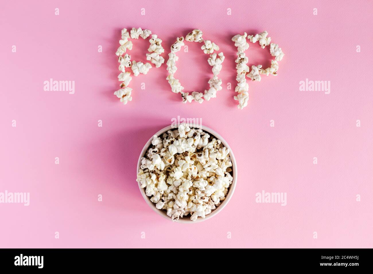 Popcorn in una ciotola rosa su sfondo rosa, vista dall'alto Foto Stock
