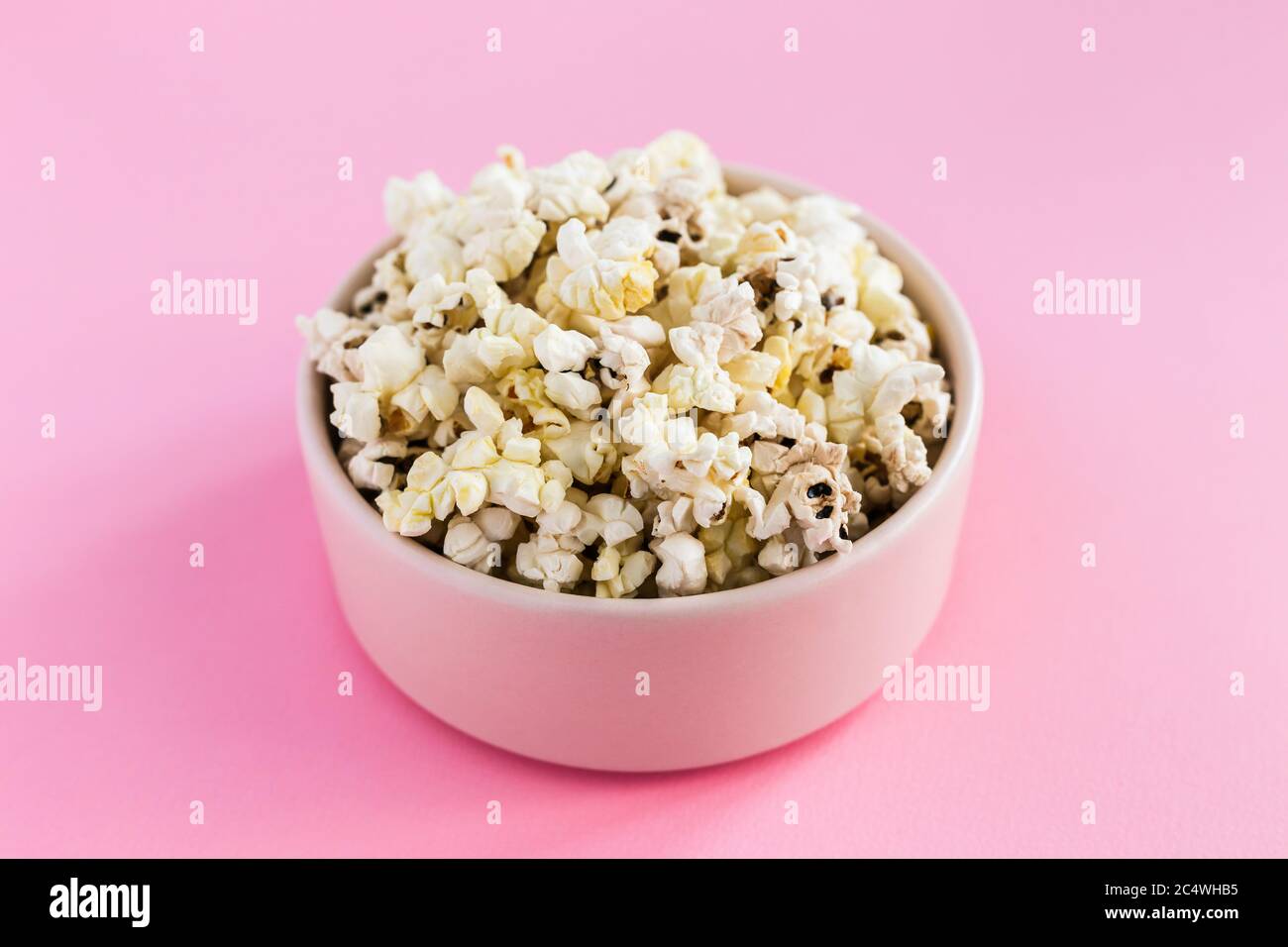 Popcorn in una ciotola rosa su sfondo rosa Foto Stock