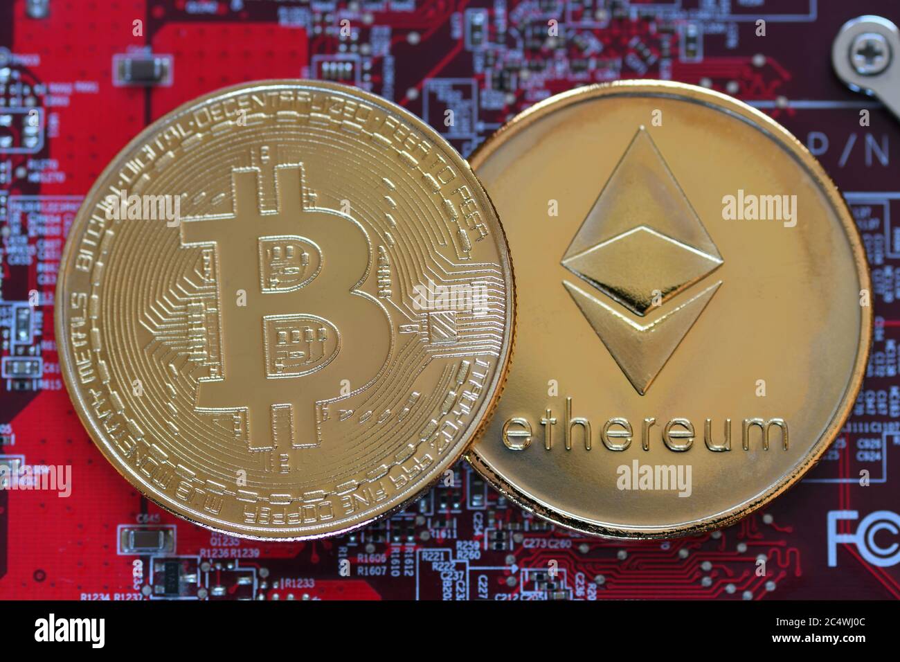 Bitcoin, BTC, bit Coin. Crypto Currency Ethereum, ETH, Cripto Coin. Macro shot di Bitcoin e monete d'oro di Ethereum su uno sfondo rosso della scheda del computer Foto Stock