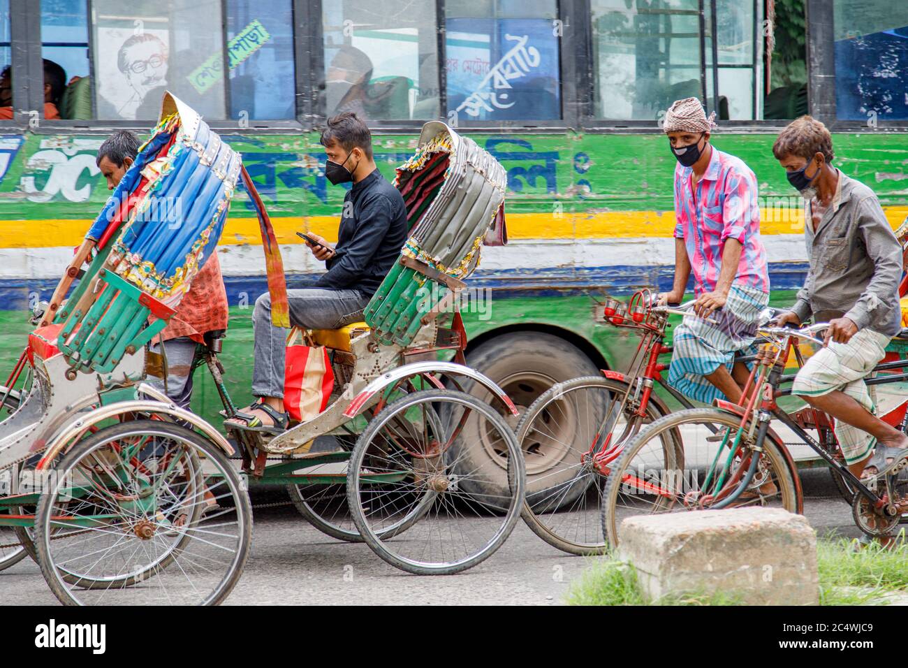 Ricksha-Walas, o risciò i conducenti con i loro passeggeri per le strade di Dacca. I residenti nella Dhaka, capitale del Bangladesh, si stanno adattando alla minaccia del virus della corona COVID 19. Foto Stock