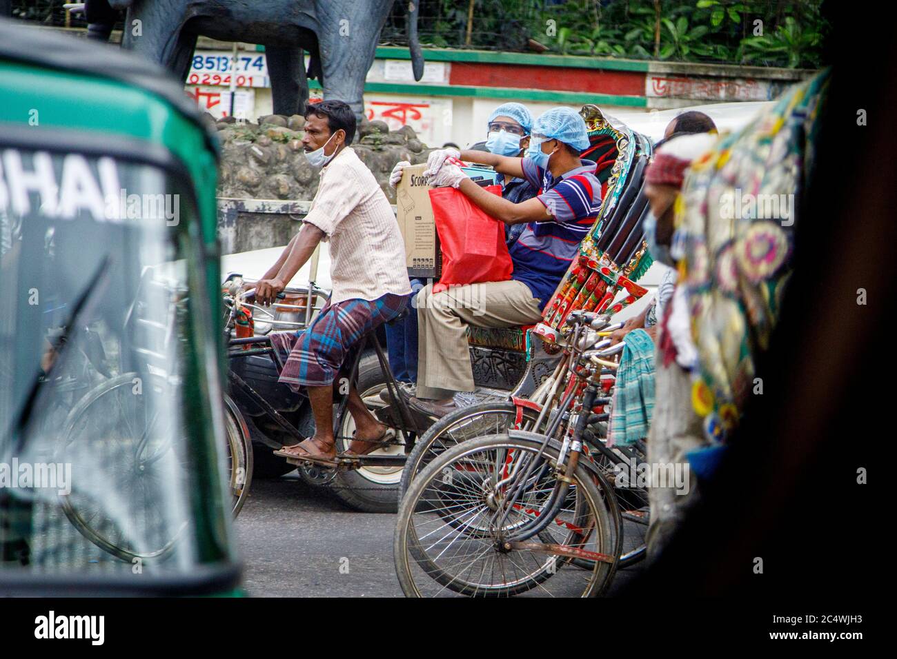 Ricksha-Walas, o risciò i conducenti con i loro passeggeri per le strade di Dacca. I residenti nella Dhaka, capitale del Bangladesh, si stanno adattando alla minaccia del virus della corona COVID 19. Foto Stock