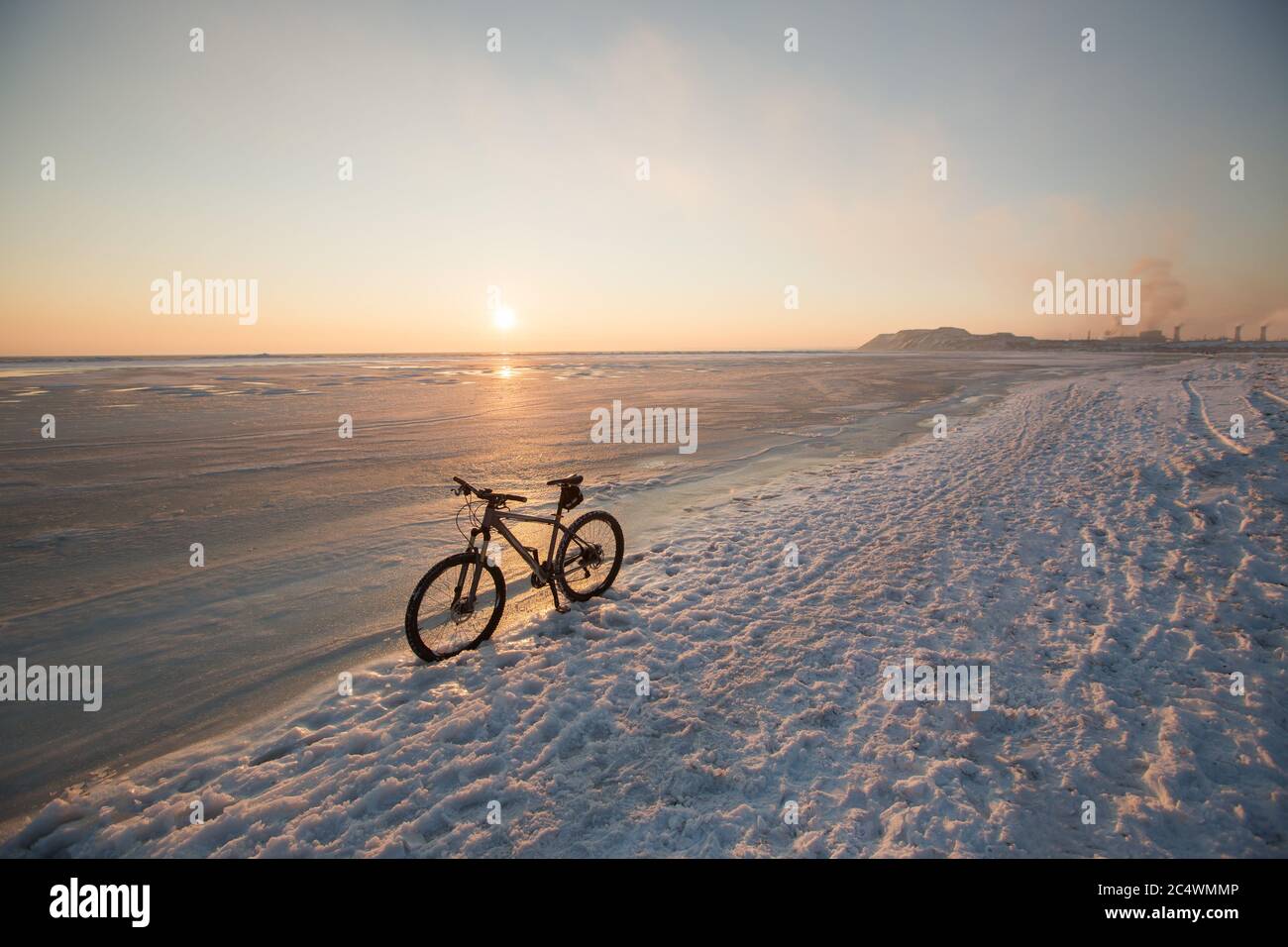 Mountain bike soggiorno nella neve vicino al mare ghiacciato o lago. Sfruttamento e manutenzione delle biciclette invernali. Pneumatici chiodati Foto Stock