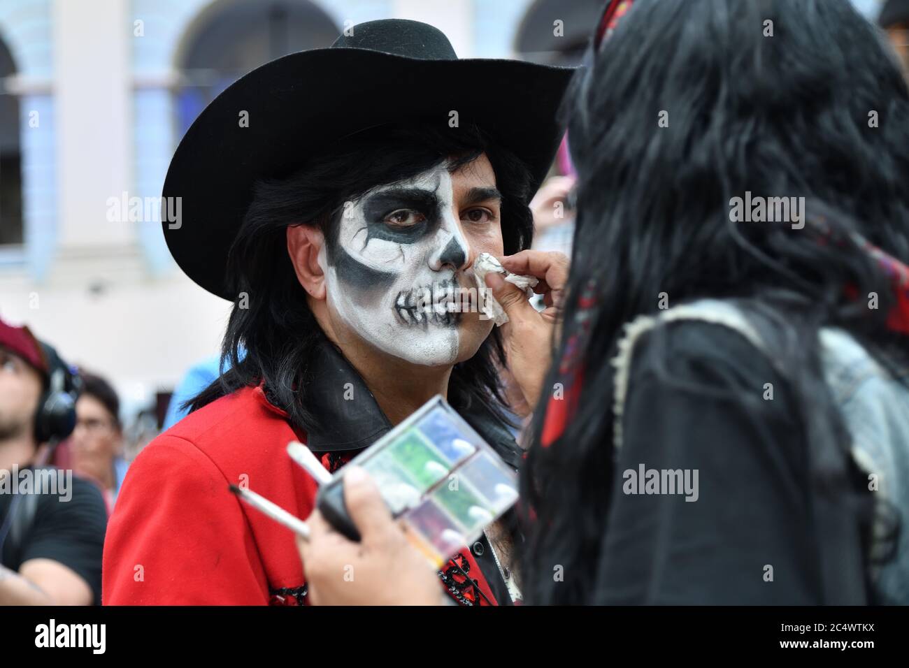 Mosca, Russia - 29 giugno 2018: La ragazza partecipante fa il trucco del  cranio di zucchero sul viso di un uomo durante il carnevale messicano di dia  de los Muertos. Giorno del