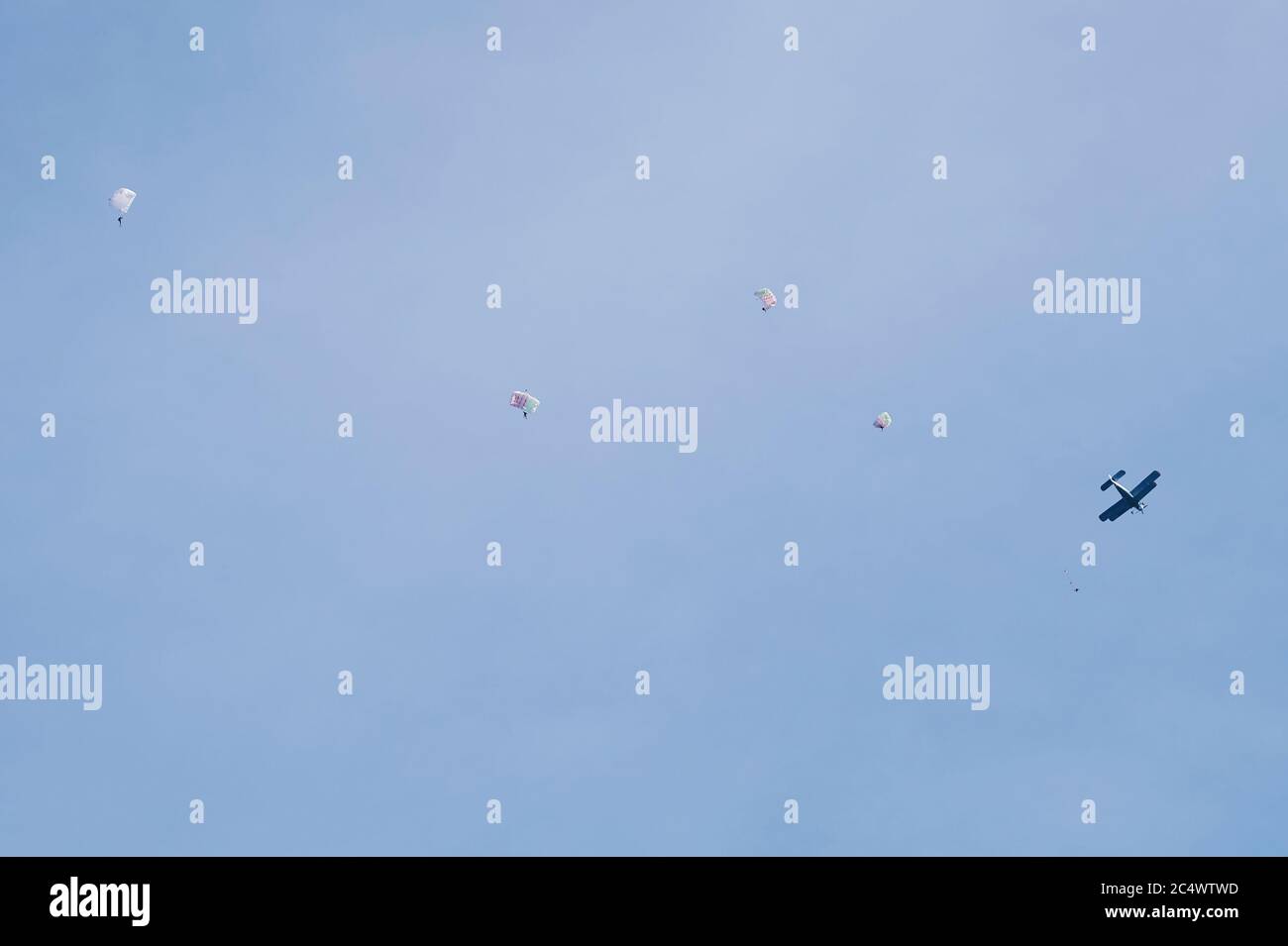 Persone che saltano dall'aereo con paracadute su sfondo blu cielo Foto Stock