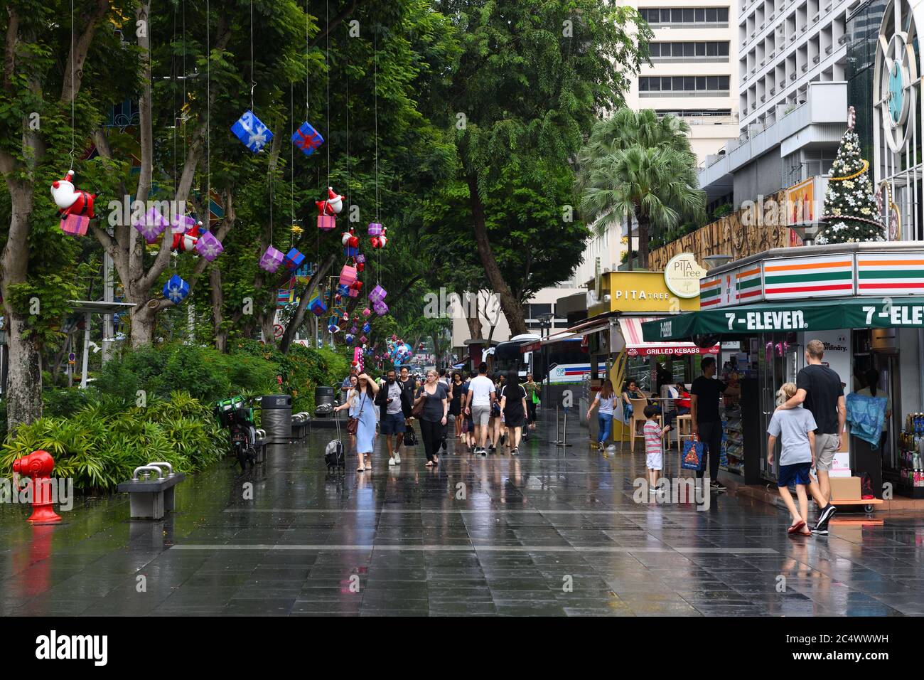 Decorazioni natalizie e shopping su un marciapiede bagnato a Singapore, Asia Foto Stock