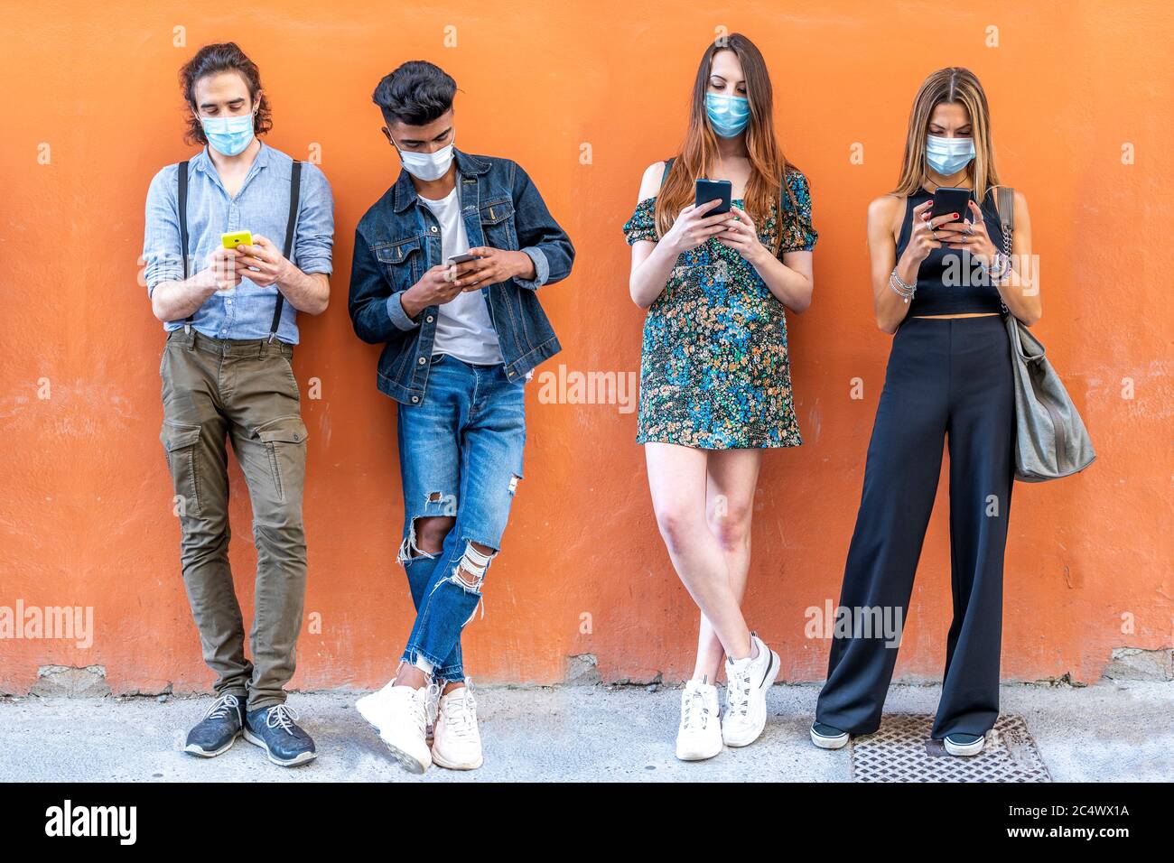 gruppo di amici multirazziali con maschere facciali che utilizzano gli smartphone per condividere contenuti sui social network Foto Stock